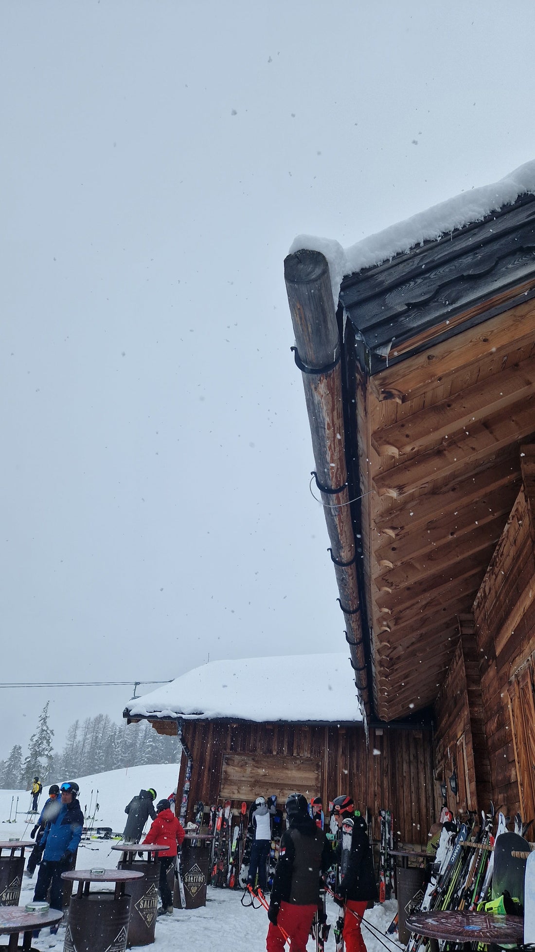 Skihütte in Ischgl im Schnee mit  Skifahrern und Abstellplatz für Ski– typische Après-Ski Atmosphäre in den Tiroler Alpen